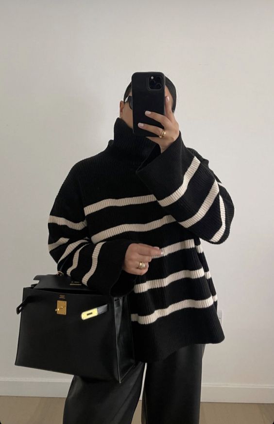 an oversized black Breton stripe sweater, black pants, a black bag are a comzy and comfy winter work look