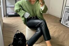 black leather pants, black loafers, a black backpack, an oversized white shirt, an oversized green pullover and a chic watch