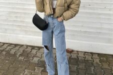 blue ripped jeans, a white sweater and sneakers, a beige cropped puffer jacket and a black bag for winter