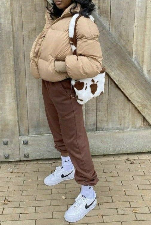 brown sweatpants, white sneakers and socks, a beige cropped puffer jacket and an animal print bag