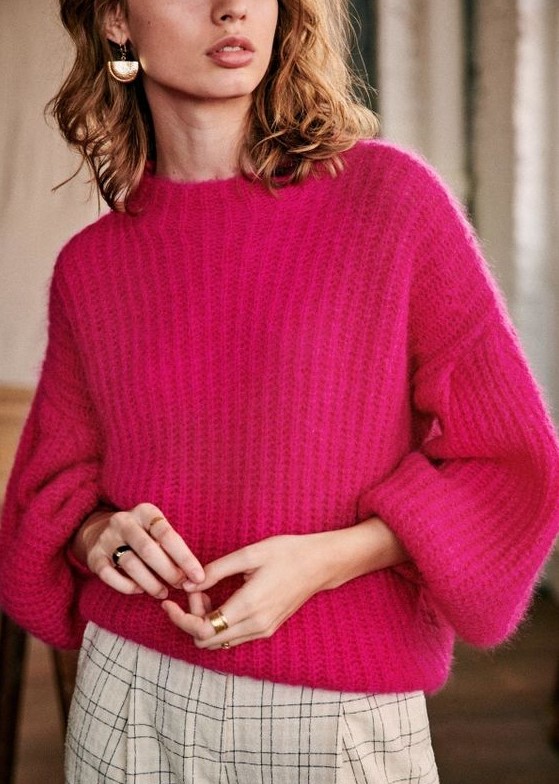 a beautiful chunky knit fuchsia sweater, neutral plaid trousers and statement earrings plus statement rings