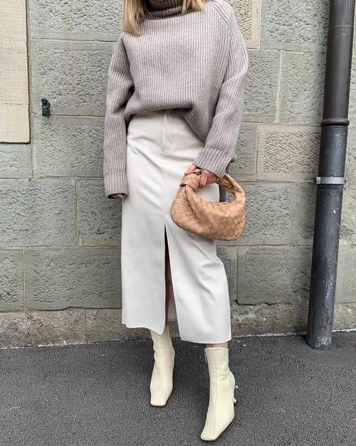 an oversized grey sweater, a white denim midi skirt, neutral boots and a beige woven bag for winter