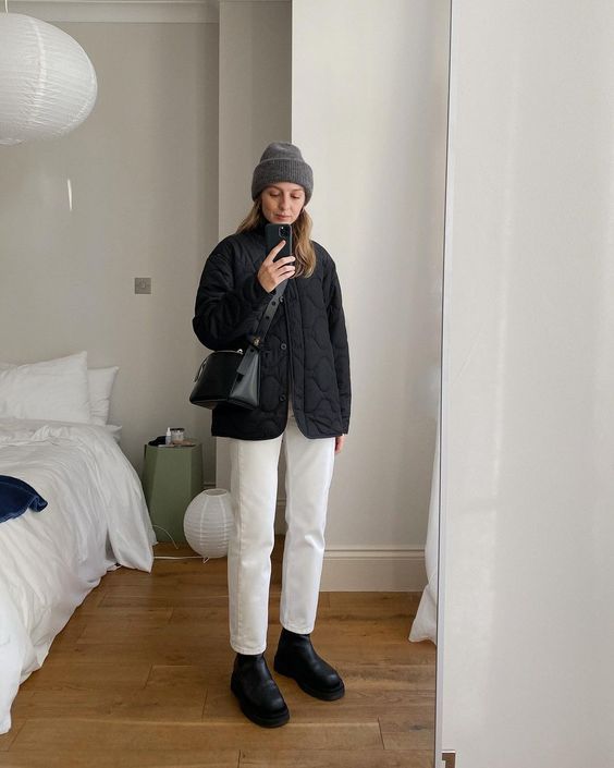 a comfortable winter outfit with white jeans, a black quilted jacket, black boots, a bag and a grey beanie