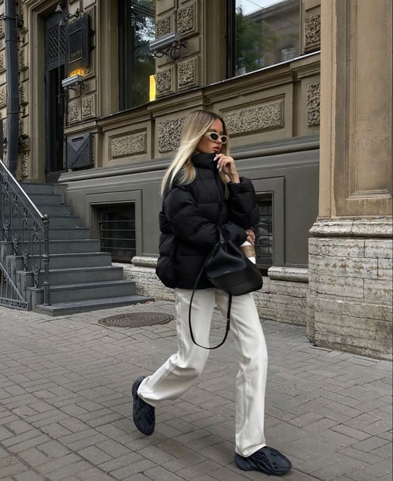 a comfy winter outfit with white jeans, a black puffer, black trainers and a black backpack is a cozy idea