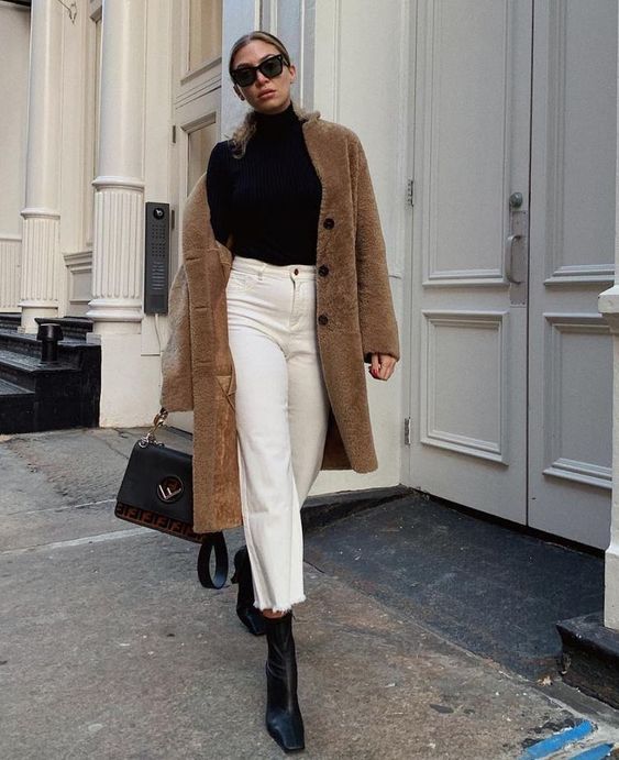 a simple and stylish winter outfit with a black turtleneck, white jeans, black boots and a bag plus a brown faux fur coat