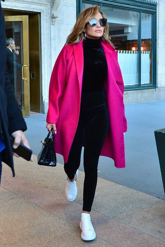 J.Lo wearing a total black look with leggings and a turtleneck spruced up with a magenta coat, white sneakers and a black bag