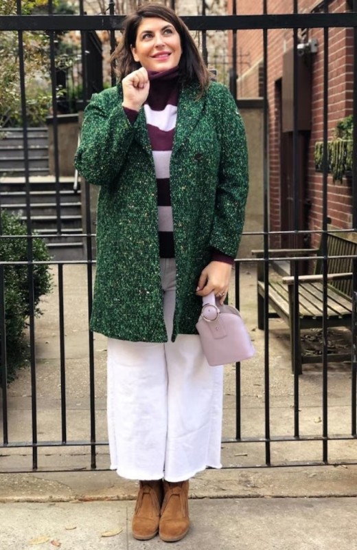 a creative outfit with a purple and white striped sweater, white wideleg jeans, tan boots, a green coat and a lilac bag