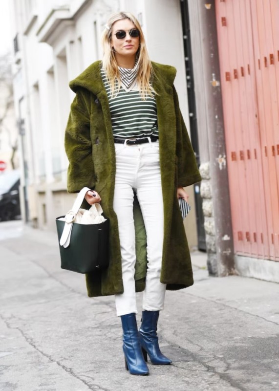 a winter look with a green striped top, white jeans, blue boots, a green faux fur coat and a black bag