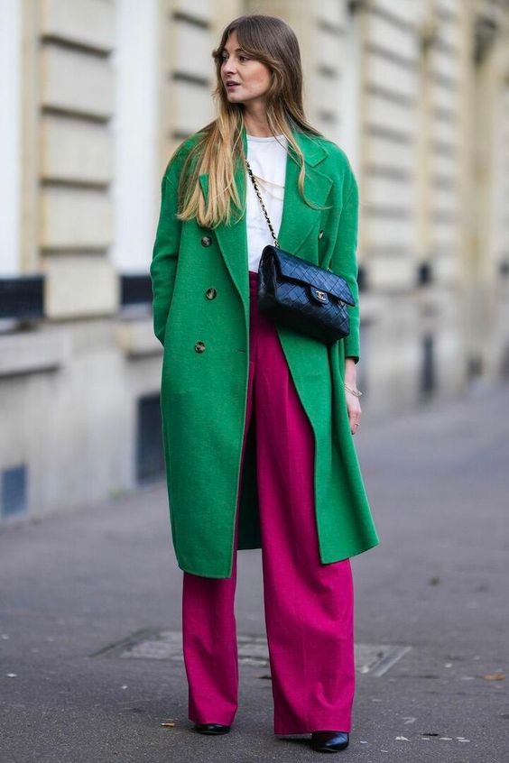 a white t-shirt, magenta pants, black boots, a green coat and a black bag are a bold combo that is comfy in wearing