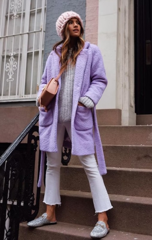 a winter outfit with a white chunky knit sweater, flare cropped jeans, snakeskin slippers, a purple coat, a beige bag