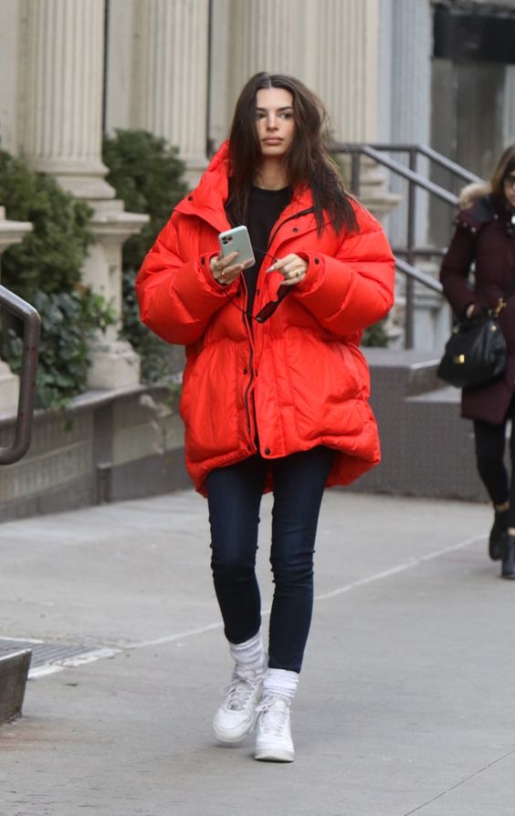 Emily Ratajkowski wearing black leggings and a sweatshirt, white sneakers and socks, a red puffer jacket