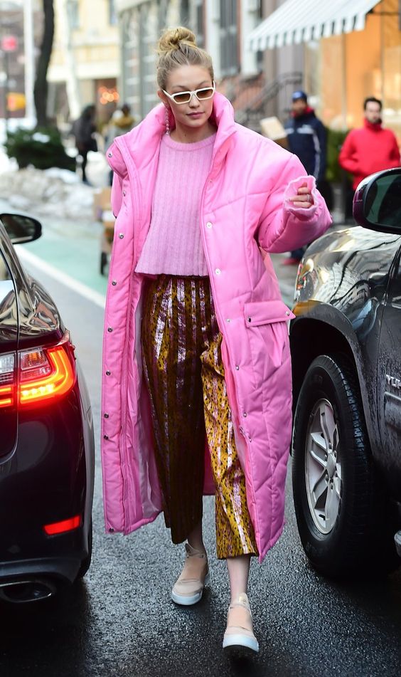 Gigi Hadid wearing a pink cropped sweater, leopard print vinyl pants, slipons and a hot pink puffer coat