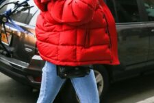 Kendall Jenner wearing blue jeans, black boots, a black waistbag and a red puffer jacket looks bold and catchy