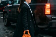 With printed shirt, black pants, orange leather bag, tights and black leather high heels