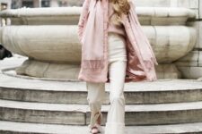 With white framed sunglasses, pale pink sweater, beige high-waisted pants, pale pink shoes and pale pink fringe scarf
