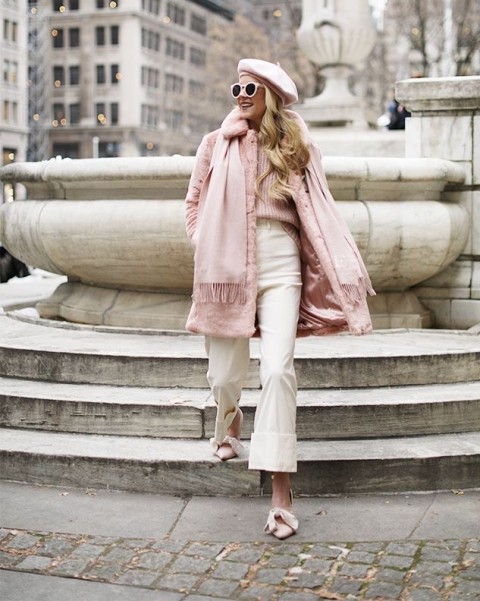 With white framed sunglasses, pale pink sweater, beige high-waisted pants, pale pink shoes and pale pink fringe scarf