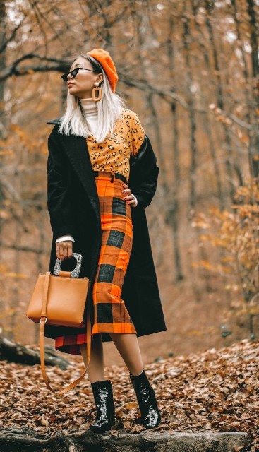 With white turtleneck, leopard printed shirt, orange and black checked high waisted midi skirt, earrings, sunglasses, brown leather bag and black patent leather mid calf boots