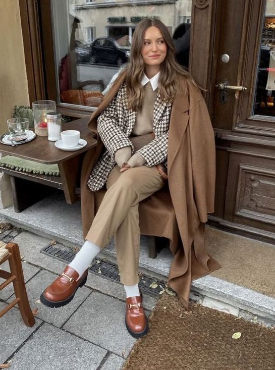 a beautiful layered winter work look with a white shirt, a tan waistcoat, a printed blazer, tan trousers, white socks, brown loafers and a brown coat