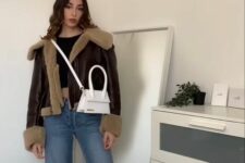 a black crop top, blue jeans, brown ugg boots, a brown cropped shearling jacket and a white bag