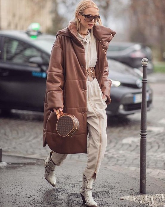 a bold and neutral outfit with a jumpsuit with a wide belt, snakeskin print boots, a brown leather puffer coat and a brown bag