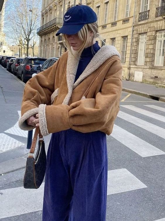 a bold electric blue with a turtleneck, trousers and a baseball cap plus a beige cropped aviator