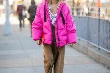 a bold winter outfit with a spotted top, brown pants, white Chelsea boots, a hot pink puffer jacket