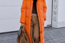 a cozy and comfortable winter look with a brown turtleneck, beige pants, a beige bag, an orange puffer coat