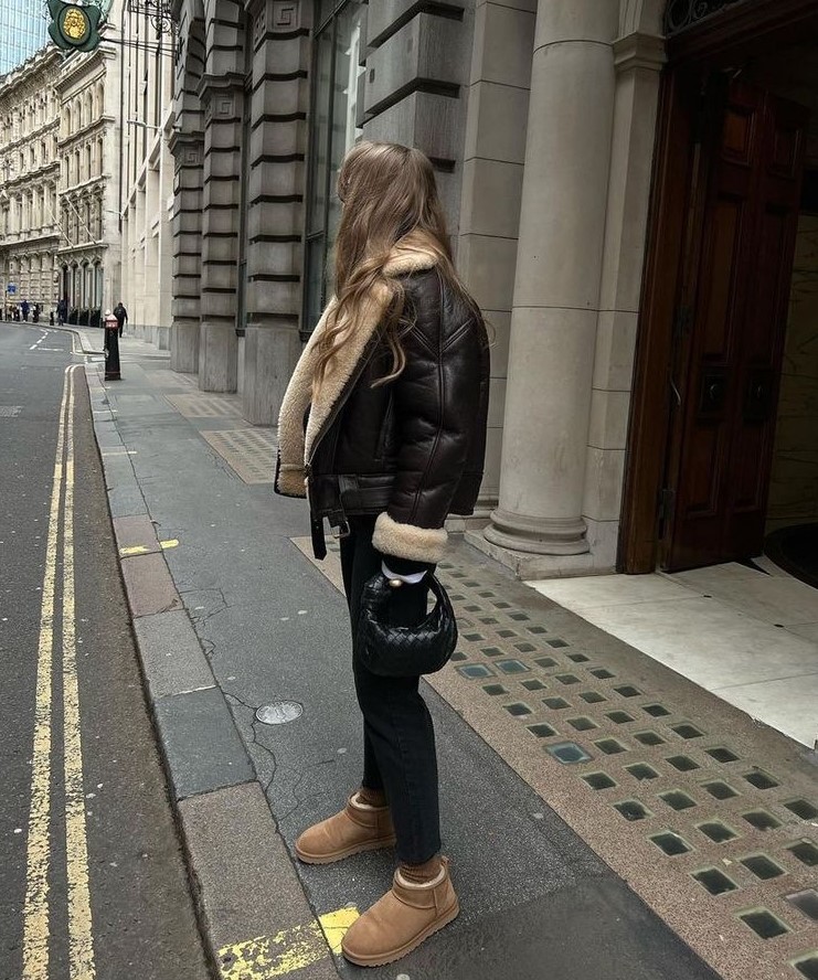 a dark brown aviator jacket, black jeans, beige ugg boots and a small black bag are pure fashion