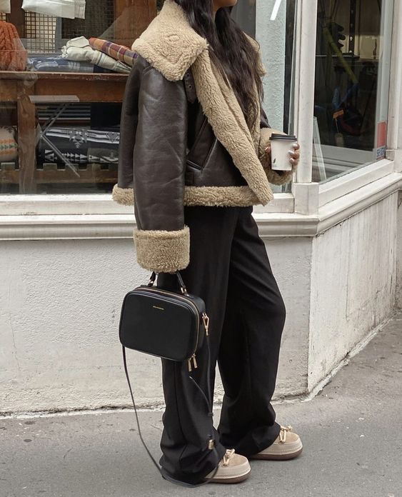 a dark brown shearling jacket, black trousers, ugg boots, a black box bag for a cozy winter look