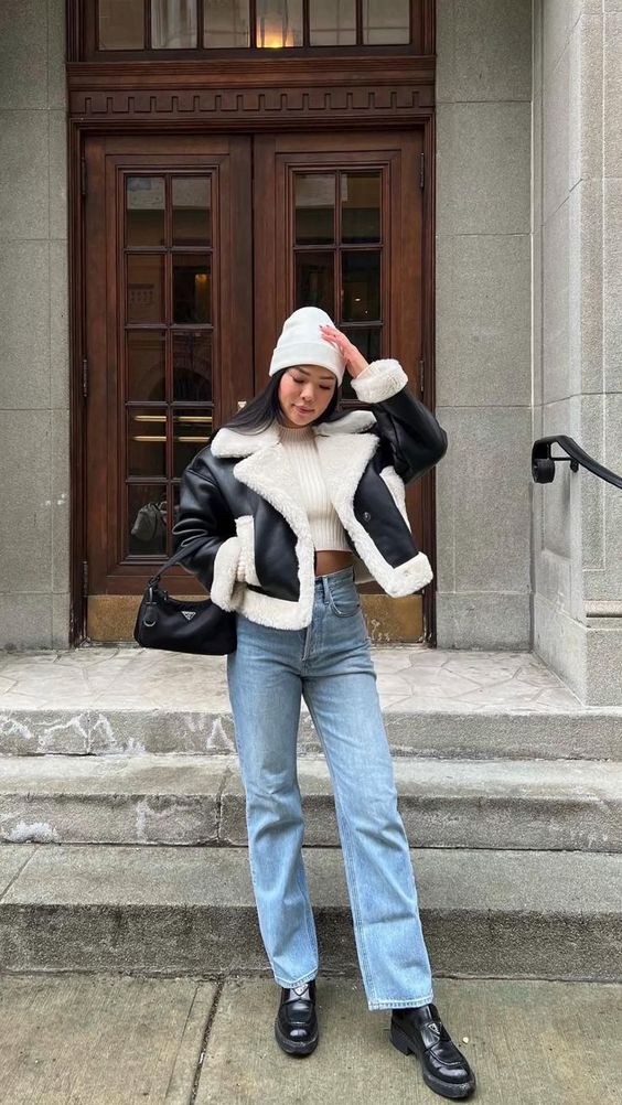 a lovely winter look with a creamy crop top, blue jeans, black boots, a black aviator and a white beanie
