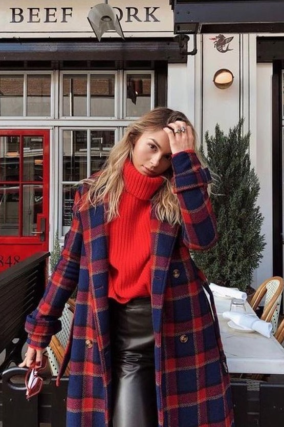 a red oversized sweater, black leather pants, a red and navy plaid coat compose a bold and colorful holiday look