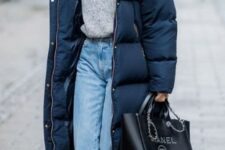 a refined winter look with a grey jumper, light blue jeans, dark green booties, a navy puffer coat and a black tote