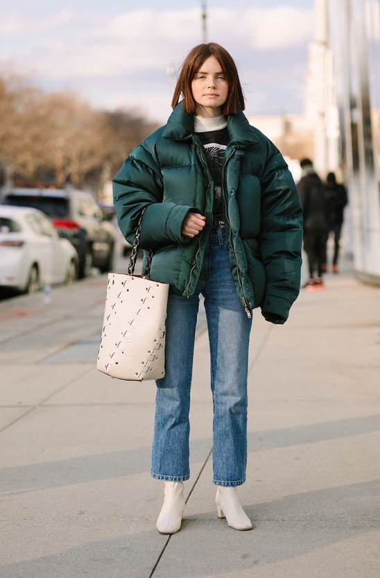 a retro-inspired look with a printed sweatshirt, blue straight jeans, white boots and a bag plus a forest green puffer jacket