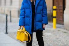 a sport chic winter look with a black zip sweater and jeans, black boots with blue laces, a blue puffer jacket and a yellow bag