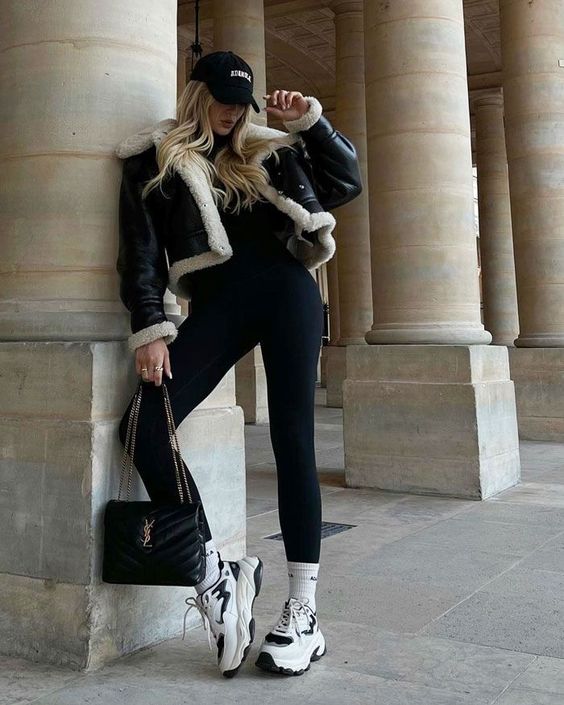 a sport chic winter outfit with a black turtleneck and leggings, white trainers and socks, a cropped shearling jacket and a black bag