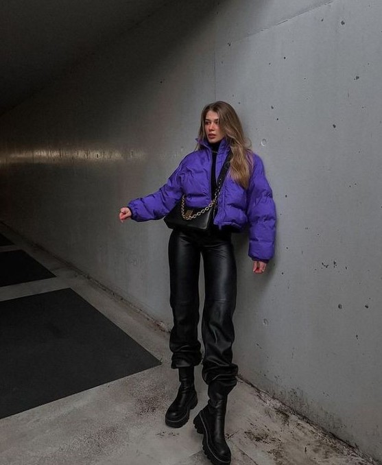 a total black look accented with a bold touch, with leather pants, boots, a turtleneck and a bag plus a bold purple cropped puffer jacket