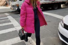 a total black outfit with leggings, chunky boots, a top and a bag accented with a fuchsia puffer jacket