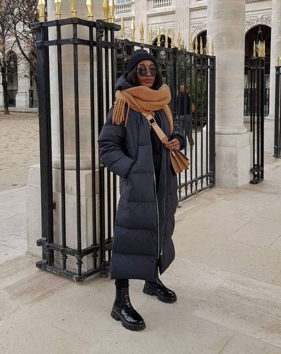 a winter outfit in and rust, with lacquer Chelsea boots, a black puffer coat, a rust scarf and a bag, a black beanie