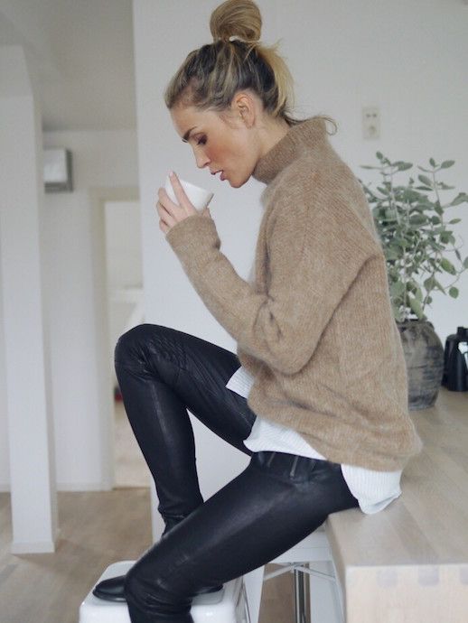 an oversized white shirt, black leather pants, a beige sweater over the shirt for a cool and cozy winter work look