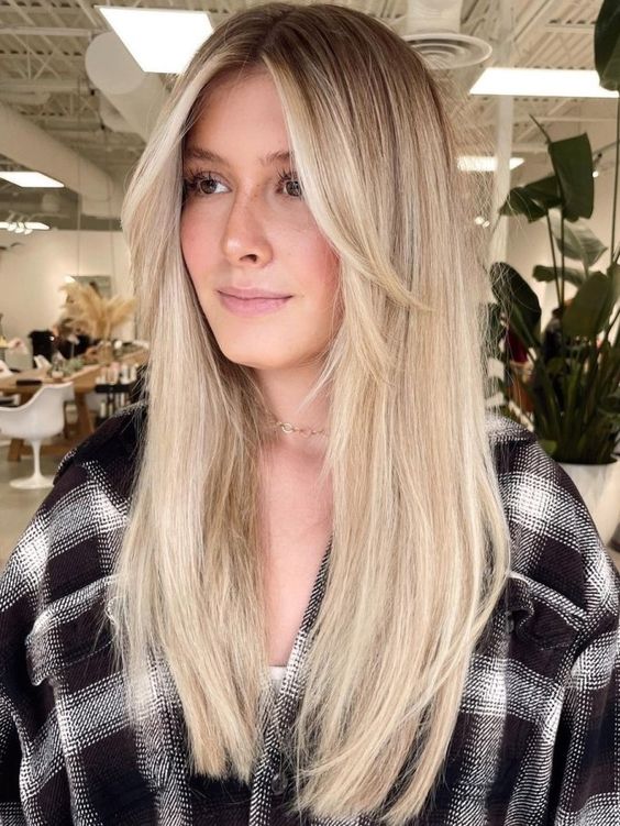 long blonde hair with long curtain bangs that add interest to the look and bring dimension to the hairstyle