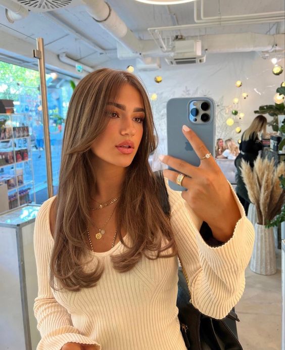 long brown hair with a cascade effect, a caramel balayage and long curtain bangs is a gorgeous idea