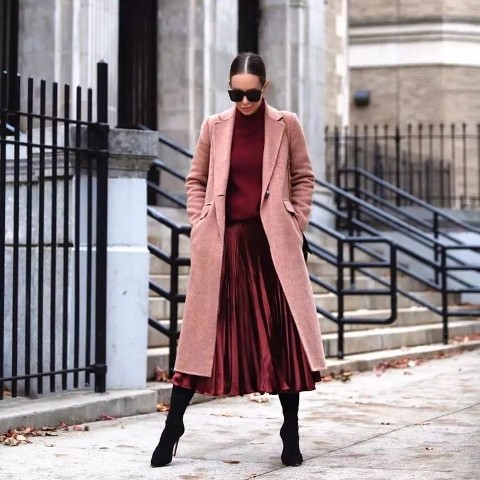 With oversized sunglasses, pale pink midi coat and black over the knee high heeled boots