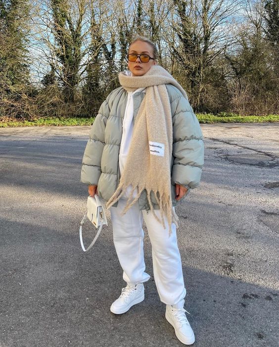 a beautiful neutral winter look with a white hoodie and sweatpants, white sneakers, a pastel green puffer jacket, a beige scarf and a white bag