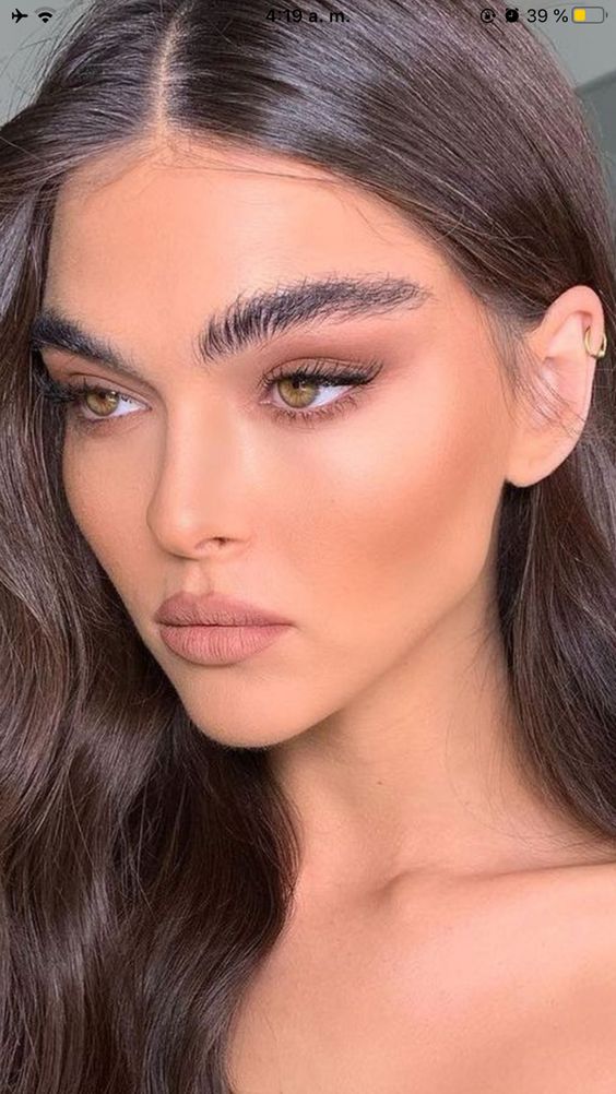 a chic makeup with a matte nude lip, matching brown smokey eyes, fluffy eyebrows, a touch of warm blush