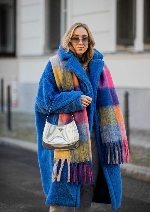 a colorful winter look with grey jeans, a bold blue teddy coat, a colorful scarf with fringe and a silver bag
