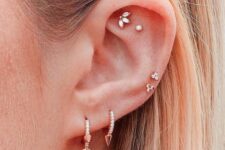 a double lobe, flat and faux rook, double mid helix piercing with rhinestone hoops and studs