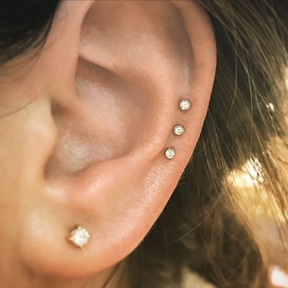 a lobe plus a triple mid helix piercings done with rhinestone studs are amazing, this is a modern and stylish solution