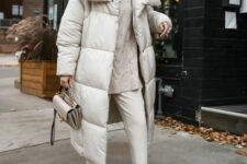 a neutral oversized sweater, creamy jeans, white sneakers, a neutral puffer coat, a grey bag compose a lovely winter look