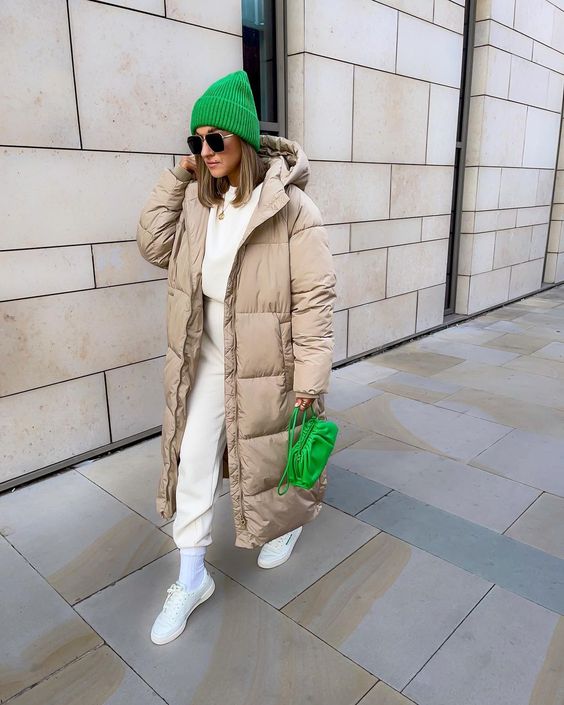 a neutral winter look with a white sweatshirt and sweatpants, white sneakers and socks, a bold green beanie and a bag