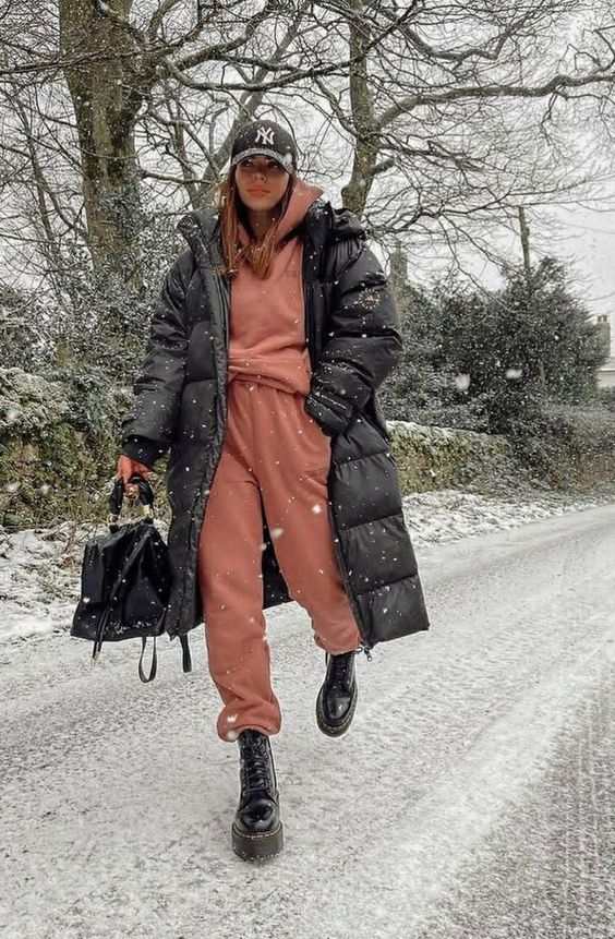a rust-colored sweatshirt and sweatpants, black chunky boots, a black puffer coat, a cap and a bag for winter